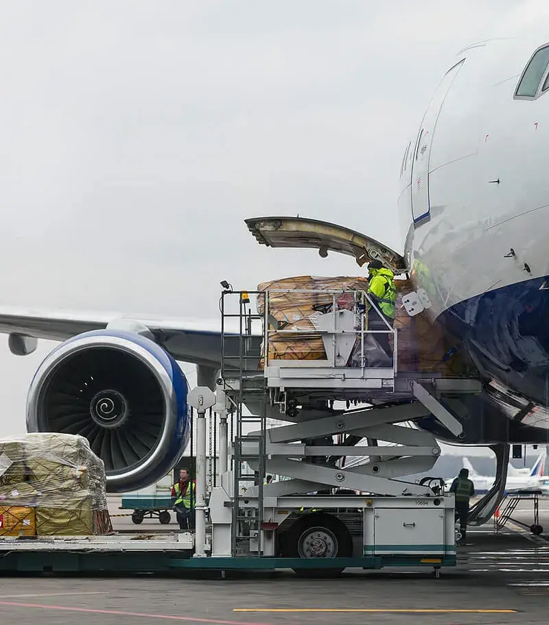 Ground crew loading palletized cargo into a freighter aircraft on the tarmac
