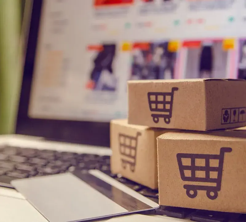 Small parcel boxes stacked on a laptop displaying an online storefront