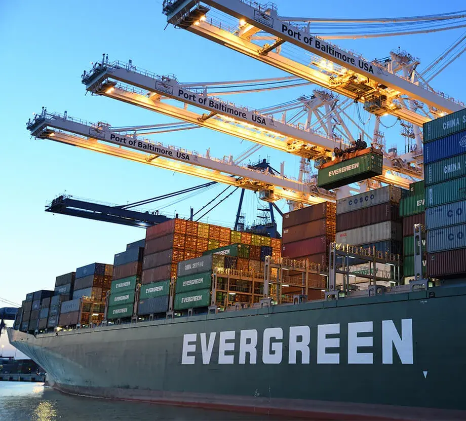 Gantry cranes loading containers onto a ship at a US port at dusk
